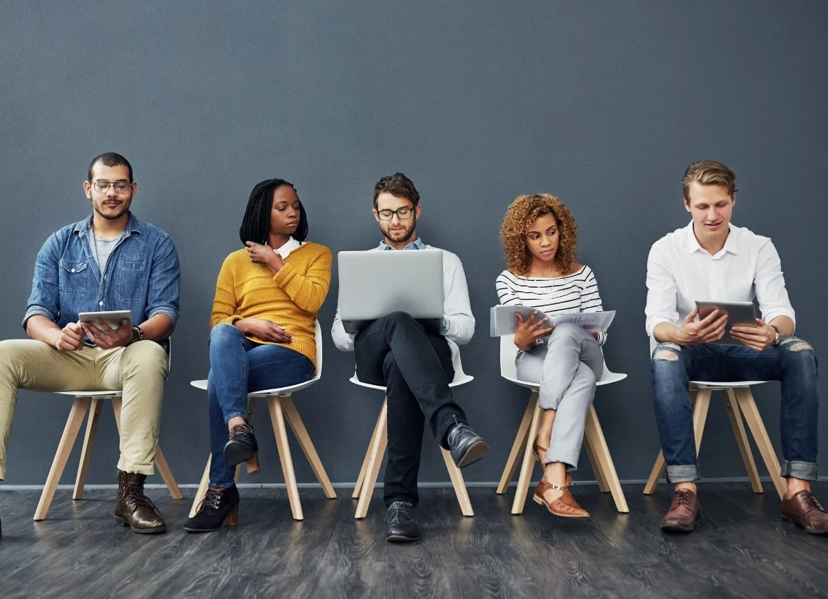 Five people using devices in a waiting area.