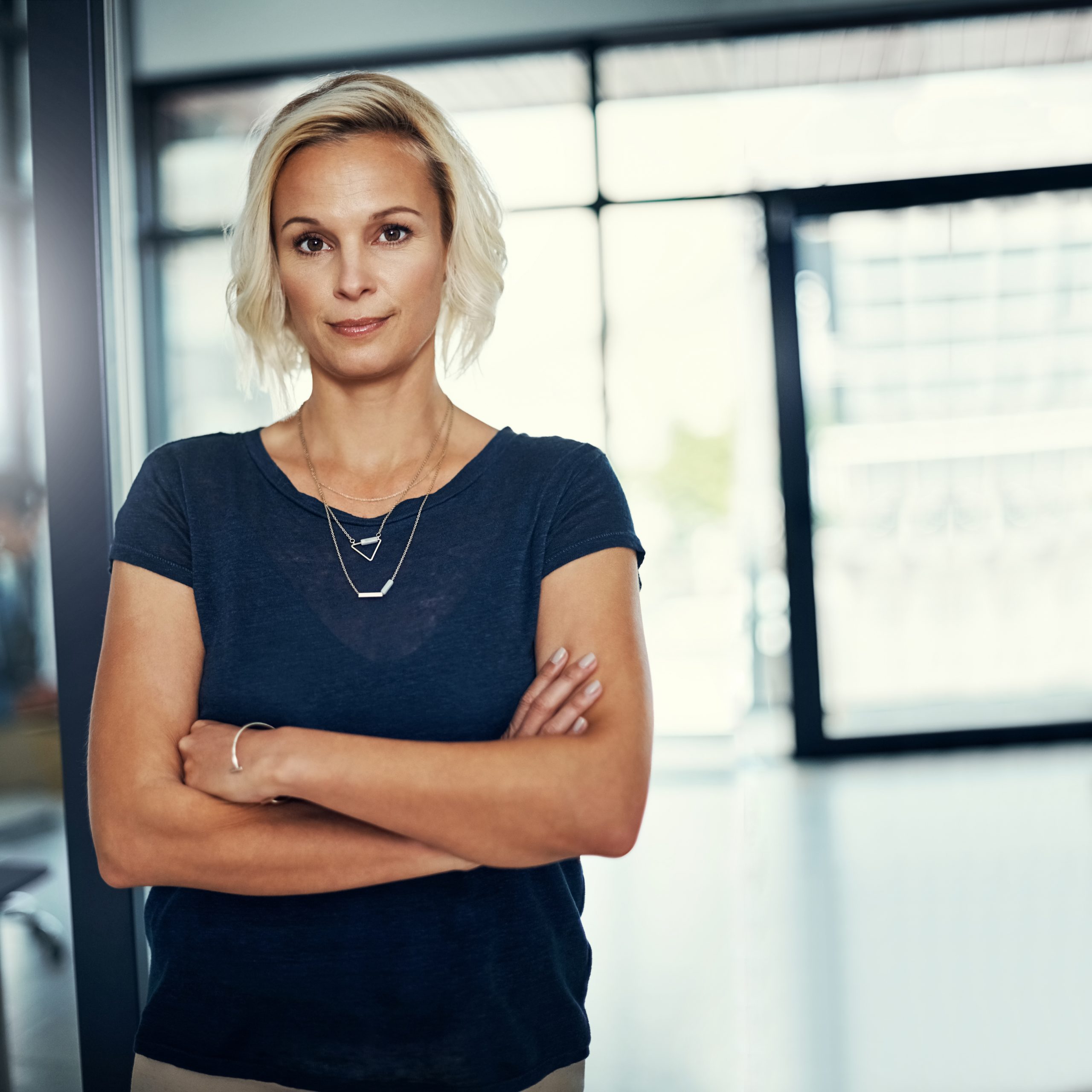 Confident woman with arms crossed indoors.